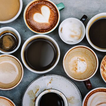 Aerial view of different sized and shaped mugs filled with coffee