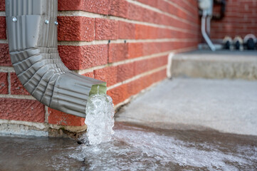 Metal downspout jammed with a frozen ice block