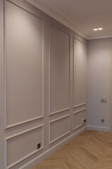 Close up view of modern and bright interior of empty cream colored corridor with herringbone parquet floor