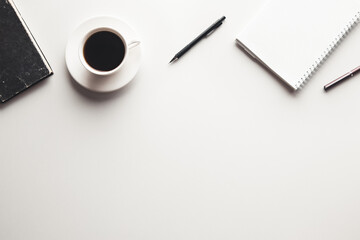 Office desk table with supplies, coffee cup and flower. Top view