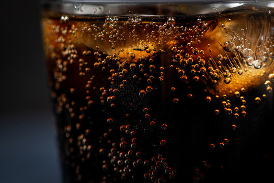 glass of coca cola with ice on a black background, closeup