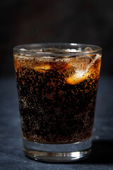 glass of coca cola with ice on a dark background, vertical closeup