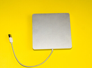  gray disk drive on  yellow background.  computer device that allows you to read and write information to removable media.