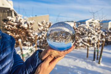 Close up macro view of hand holding crystal ball with inverted  image of winter natural landscape. Sweden.