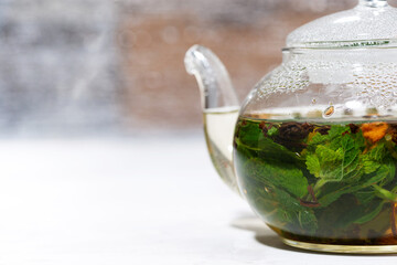 glass teapot tea with fresh mint and lemon on white background