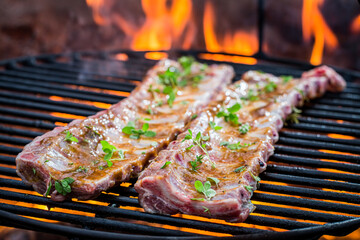 Spicy ribs with thyme and spices on grill with fire
