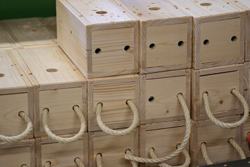 Strukturiert gestapelte, helle Holzk&auml;sten in einer Tischler-Werkstatt w&auml;hrend der Fertigstellung mit und ohne Kordelgriff