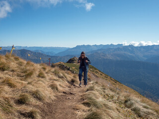 Obraz premium young female tourist with a backpack is walking in the mountains, traveling in national parks. Local tourism, beautiful nature, valleys and mountains