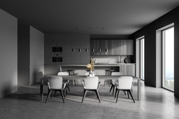 Modern kitchen interior with gray walls, a concrete floor and gray and wooden countertops. A long table with chairs near it. 3d rendering