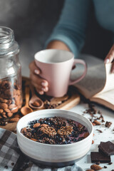 Healthy breakfast, muesli with berries and orange juice served on glass table and books. manicure