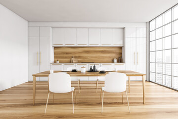 White and wooden kitchen and dining table with chairs near window