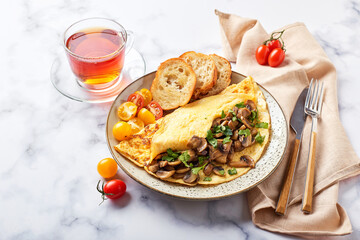 Omelet with champignons and parsley in plate on marble background. Frittata - italian omelet for breakfast or lunch.