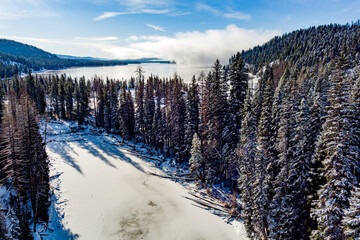 Frozen river in a winter forest leads to a lake