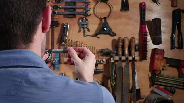 Engineer Measures Metal Part Using Micrometer in Over the Shoulder Shot