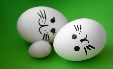 3 funny Pretty eggs on green background. Faces on the eggs. Concept family. Selective focus.