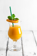 Fresh orange juice in a glass on a white wooden table. Selective focus.