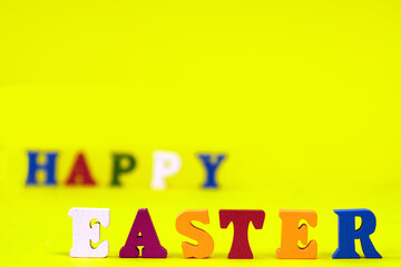 Word Happy Easter of colorful toy alphabet letters isolated on yellow background.