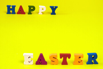 Word Happy Easter of colorful toy alphabet letters isolated on yellow background.