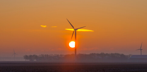 Wind turbine in an agricultural field in sunlight at sunrise in an early winter morning, Almere, Flevoland, The Netherlands, January 31, 2021