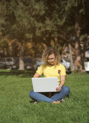 Woman in mask works with laptop outdoors 