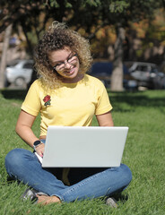 Woman in mask works with laptop outdoors 