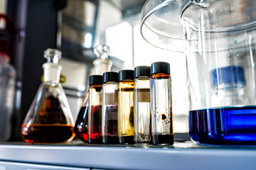 Closeup of laboratory glassware filled with orange and brown oily liquids, science and research background, selective focus