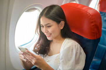 Beautiful woman traveller is using smartphone on airplane