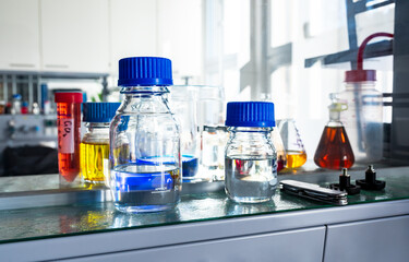 Closeup of laboratory glassware filled with various colored liquids, science and research background, selective focus