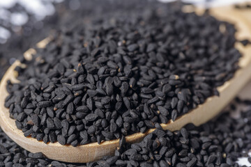 dried Nigella sativa seeds on a wooden spoon