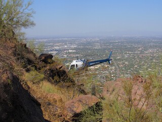 View of a hiker being airlifted from a dangerous situation on Camelback Mountain using a Phoenix Police helicopter in Arizona
