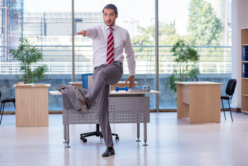 Young male employee doing sport exercises in the office