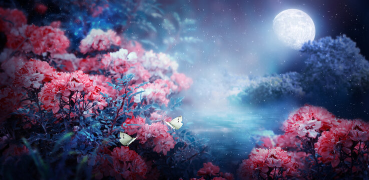 Fantasy magical enchanted fairy tale landscape with forest lake, fabulous fairytale blooming pink rose flower garden and two butterflies on mysterious blue background and glowing moon ray in night