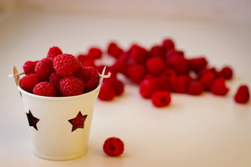 Red ripe and juicy raspberry in a small white bucket with stars