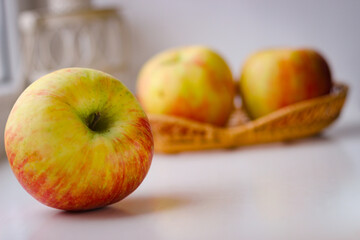 A few ripe apples on a white surface. Rear background is blurred
