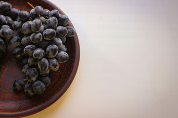 Blue grapes on a clay plate with copy space