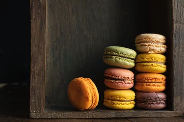 Crédence de cuisine en verre imprimé Macarons Stack of classic delicious macaroons or macarons in a dark drawer of an old sideboard, close-up