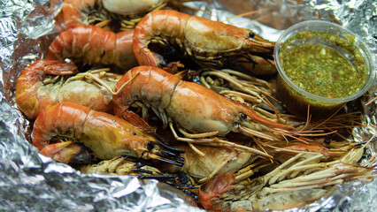 Grilled Shrimp with Seafood Sauce Contained in aluminum foil food wrap and foam food container. Thai style seafood sauce, spicy and sour taste, main ingredient, lime juice, fresh chili, fish sauce