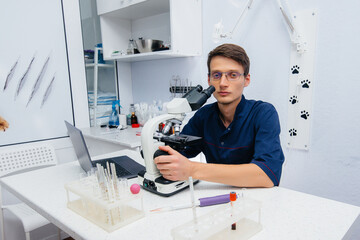 A male doctor in the laboratory studies viruses and bacteria under a microscope. Research of dangerous viruses and bacteria