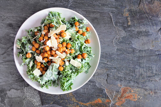 Vegetarian Caesar Salad With Chickpeas, Kale And A Yogurt Dressing. Top Down View On A Dark Slate Background. Plant Based Food Concept.