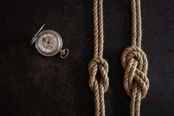 Flat lay composition on a dark background of a steel vintage pocket watch with an open lid and two...