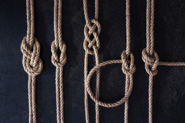 Flat lay set of five nautical knots tied on natural ropes. Ropes are parallel on a dark background © Igor
