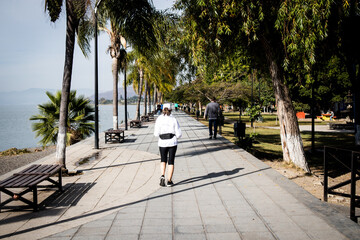 Fototapeta na wymiar Woman jogging in the morning on the boardwalk (malecón) of Lake Chapala in Ajijic, Jalisco, Mexico.