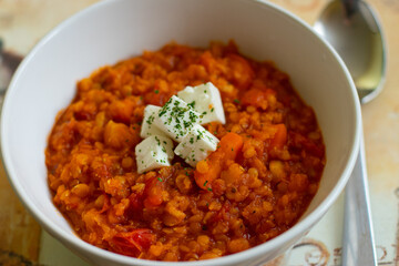 Red lentils pottage with cheese and parsley in a white bowl