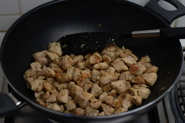 Cooking chicken cubes in a black frying pan