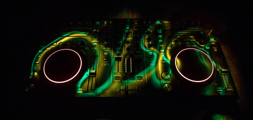 DJ console deejay-mixing desk in dark with colorful light. Mixer equipment entertainment DJ station.