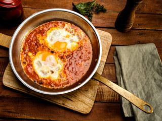 Ratatouille with egg to the pan, on classic wooden table, pan rustic of iron and cooper