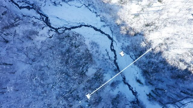 Aerial drone view of Lift cabins in a mountain ski resort  and  trees with snow  in the forest in winter