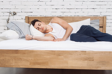 Man sleeping on a white pillow and a mattress on a wooden bed. Concept of comfortable sleep. orthopedic mattress and pillow