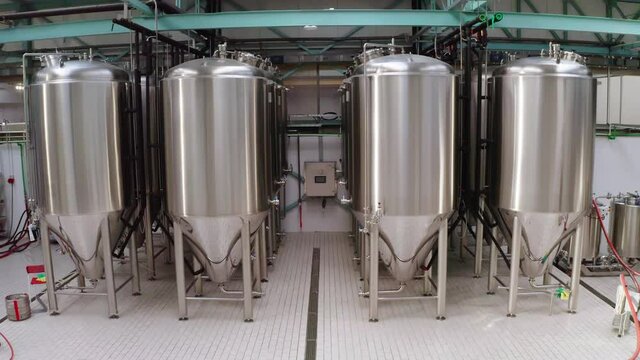 View from descending camera on four rows of cylindrical shiny steel tanks. Food production process control concept.