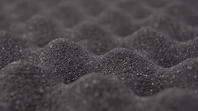 Cushioning porous foam protective material. Abstract wavy bumpy dark dusty abstract background. Macro shot. Rotation